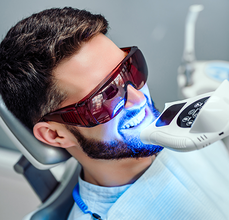 A man receiving a dental cleaning with ultraviolet light.